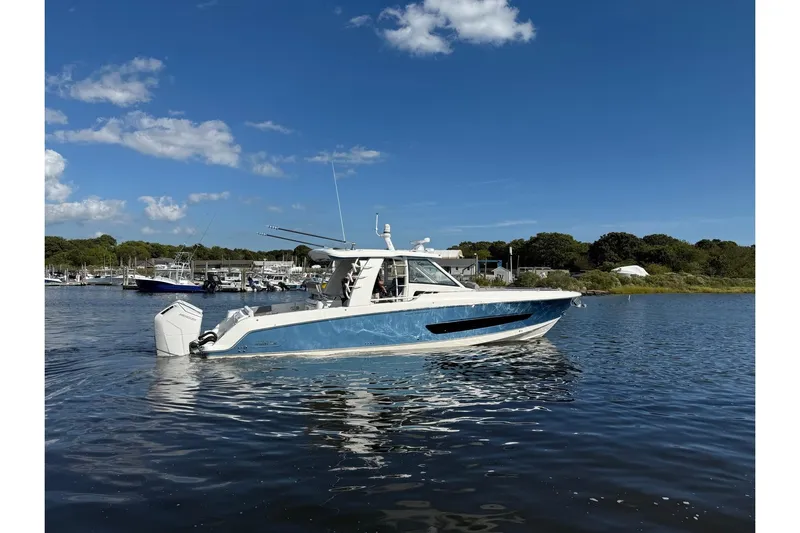  Yacht Photos Pics 2024 Boston Whaler 420 Outrage boat on calm water under clear blue sky.