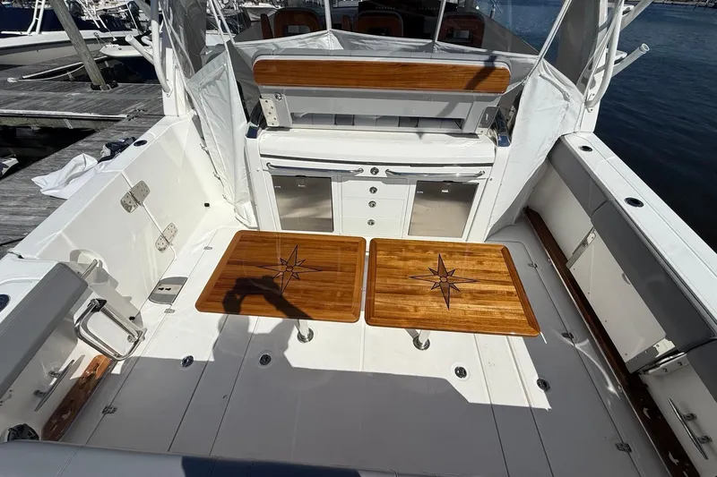  Yacht Photos Pics 2024 Boston Whaler 420 Outrage boat interior with wooden tables and seating area.