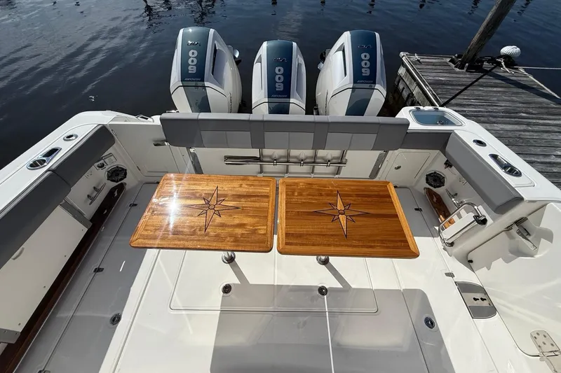  Yacht Photos Pics 2024 Boston Whaler 420 Outrage boat deck with wooden tables and triple outboard engines.