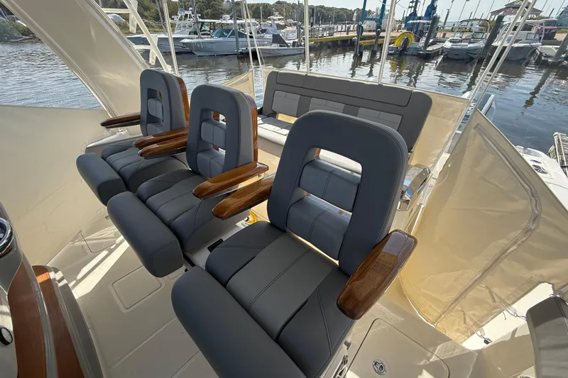  Yacht Photos Pics 2024 Boston Whaler 420 Outrage helm seats with wooden armrests, docked at marina.