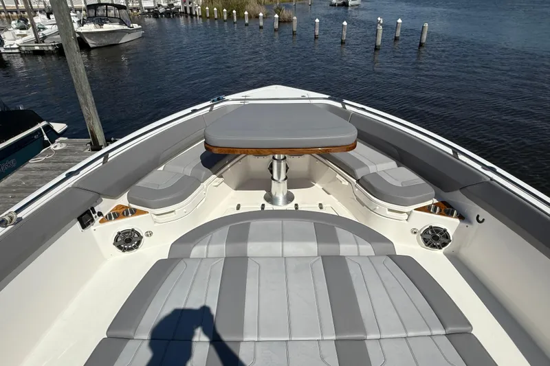  Yacht Photos Pics 2024 Boston Whaler 420 Outrage boat interior with cushioned seating and table on the water.