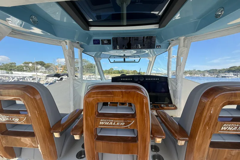  Yacht Photos Pics Interior view of 2024 Boston Whaler 420 Outrage boat with wooden seating and modern controls.