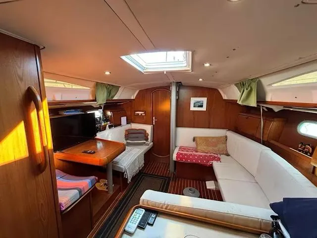 Yacht Photos Pics Interior of 2002 Jeanneau Sun Odyssey 40 sailboat with cozy seating and wooden finishes.