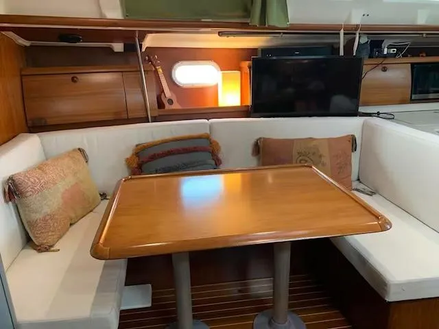  Yacht Photos Pics Cozy interior of 2002 Jeanneau Sun Odyssey 40 sailboat with wooden table and cushioned seating.
