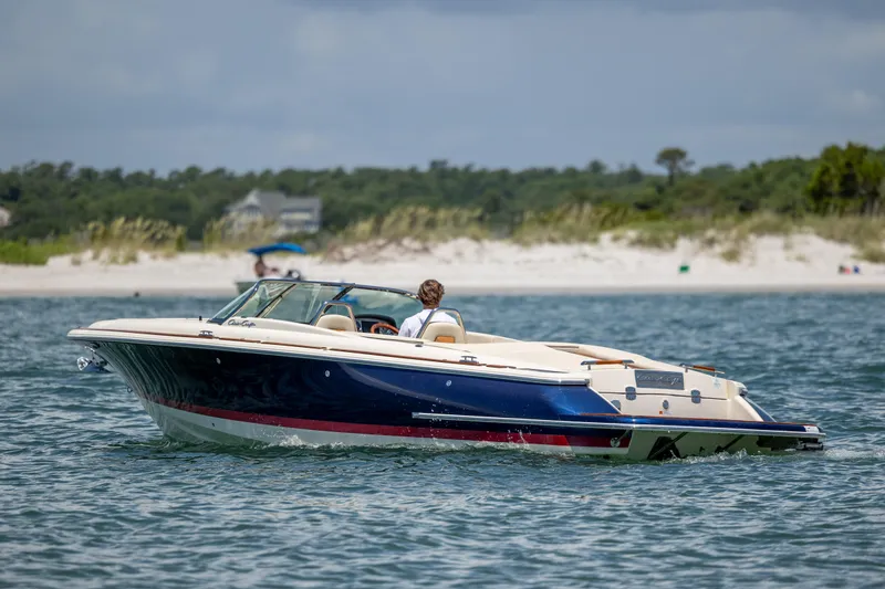  Yacht Photos Pics 2022 Chris-Craft Launch 27 boat cruising near a sandy beach.