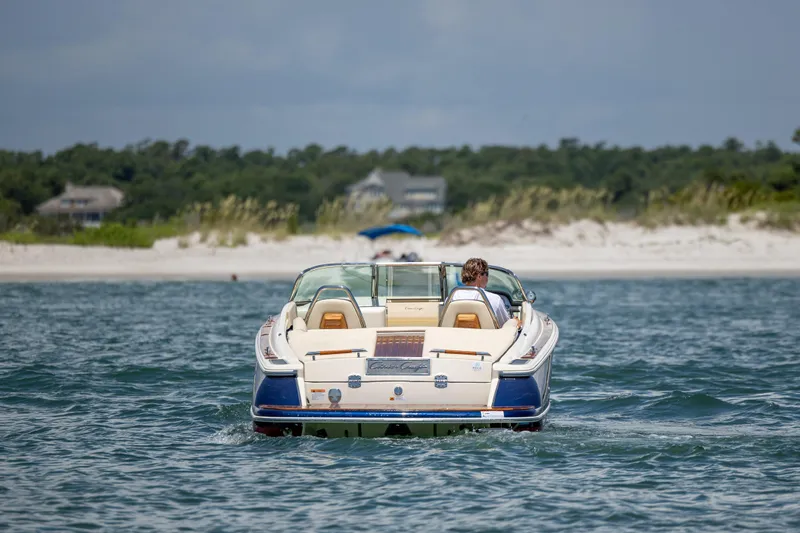  Yacht Photos Pics 2022 Chris-Craft Launch 27 boat cruising near a sandy beach.
