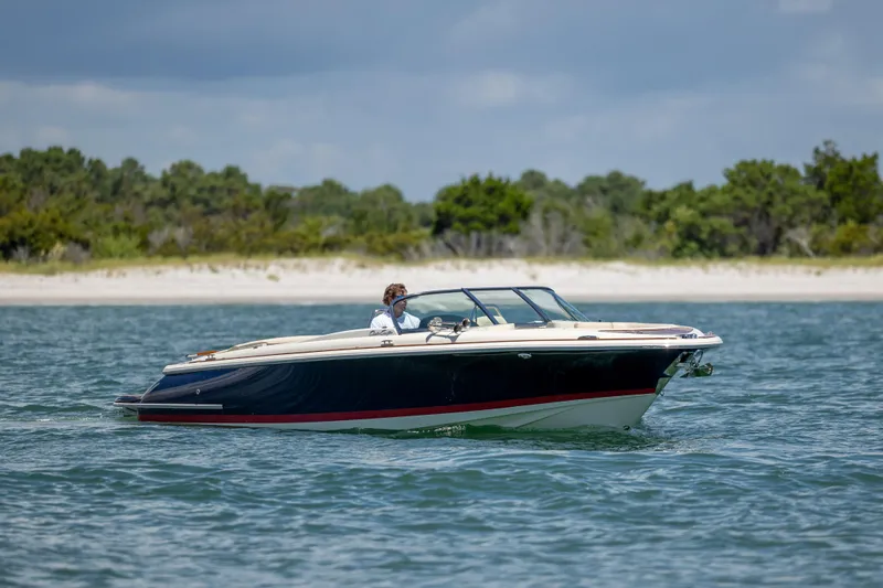  Yacht Photos Pics 2022 Chris-Craft Launch 27 boat cruising on water near a sandy shoreline.