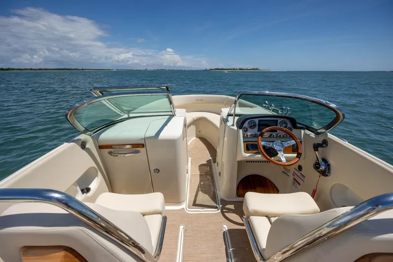  Yacht Photos Pics 2022 Chris-Craft Launch 27 boat interior with steering wheel, dashboard, and seating on open water.