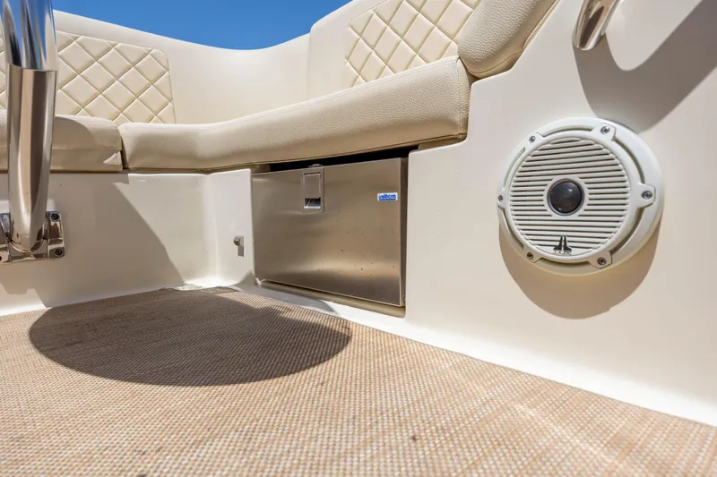  Yacht Photos Pics 2022 Chris-Craft Launch 27 interior with beige seating, speaker, and stainless steel compartment.