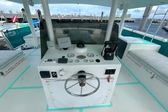 Keylypso Yacht Photos Pics Helm of 1998 Custom Catamaran with navigation equipment and steering wheel, docked at marina.