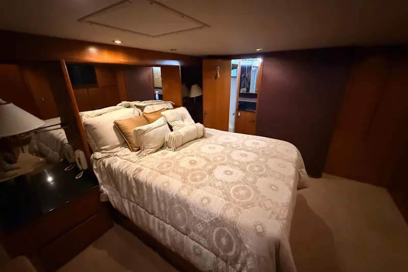 Bonnie Jean Yacht Photos Pics Luxurious bedroom in 1998 Ocean Alexander Pilothouse Model 584 yacht, featuring elegant bedding and wood paneling.