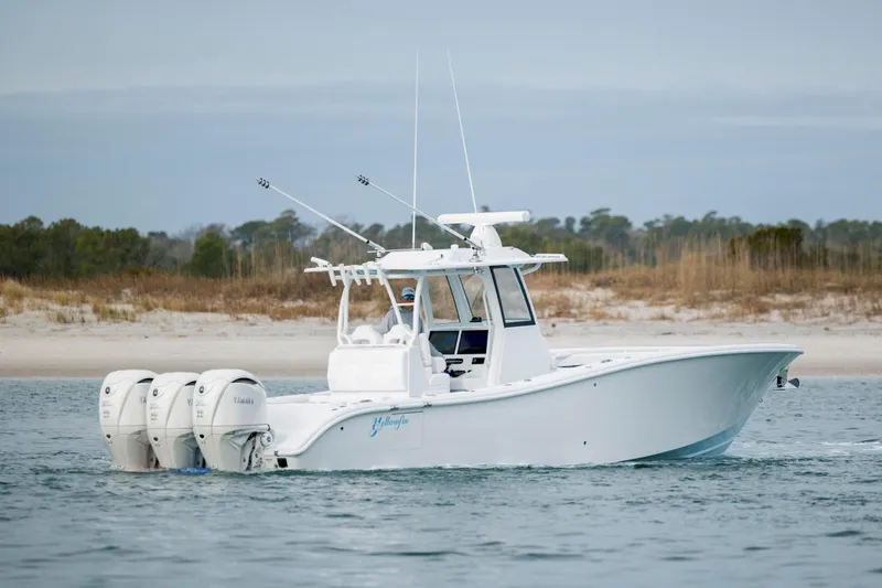  Yacht Photos Pics 2026 Yellowfin 36 Offshore boat with triple engines near a sandy shoreline.