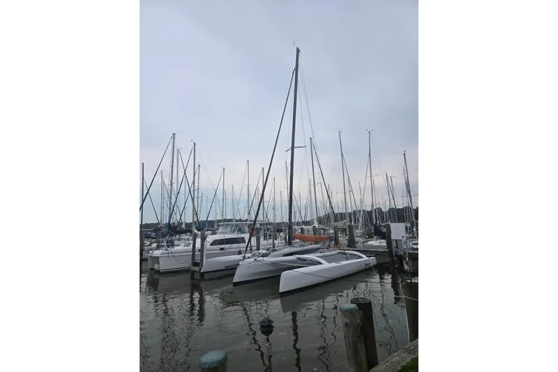 Crush Yacht Photos Pics 2022 Corsair 880 Sport sailboat docked among other boats in a marina.