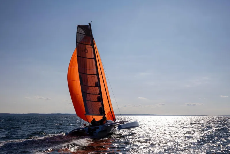 Crush Yacht Photos Pics Sailing Corsair 880 Sport 2022 with vibrant orange sail on open water.