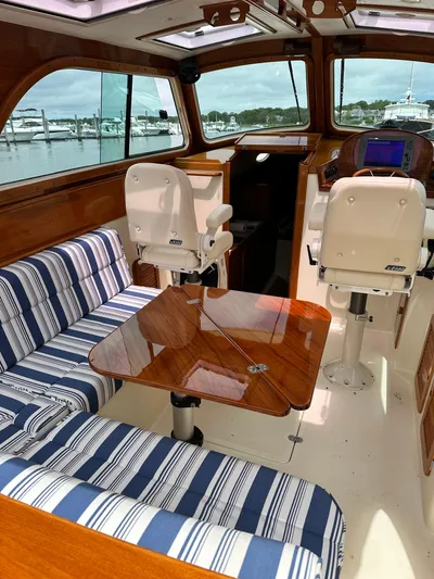  Yacht Photos Pics Interior of a 2005 Hinckley 36 boat with striped seating and wooden table.