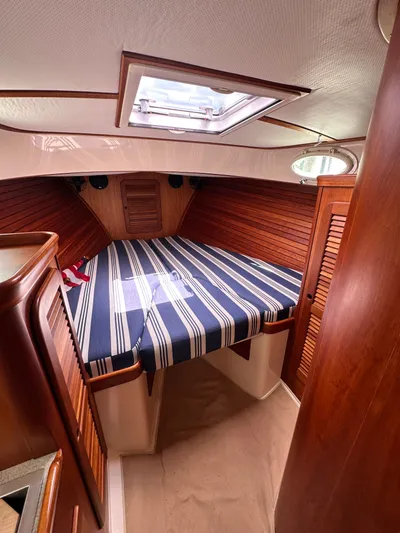  Yacht Photos Pics 2005 Hinckley 36 yacht cabin with striped bedding and wooden interior.