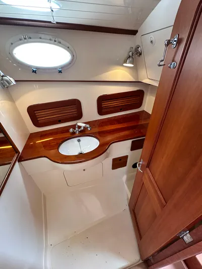  Yacht Photos Pics 2005 Hinckley 36 yacht bathroom with wooden countertop, sink, and porthole window.