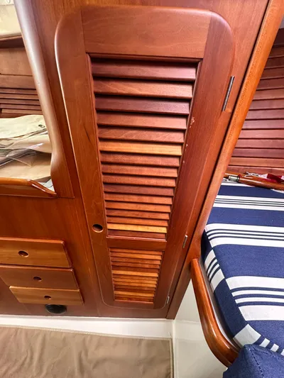  Yacht Photos Pics Wooden interior of a 2005 Hinckley 36 boat, featuring louvered cabinet and striped cushion.