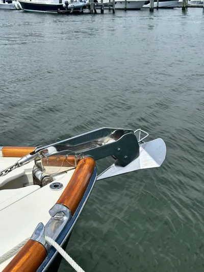  Yacht Photos Pics Bow of a 2005 Hinckley 36 boat with anchor, docked on calm water.