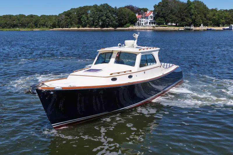  Yacht Photos Pics 2005 Hinckley 36 boat cruising on a scenic lake with a mansion in the background.