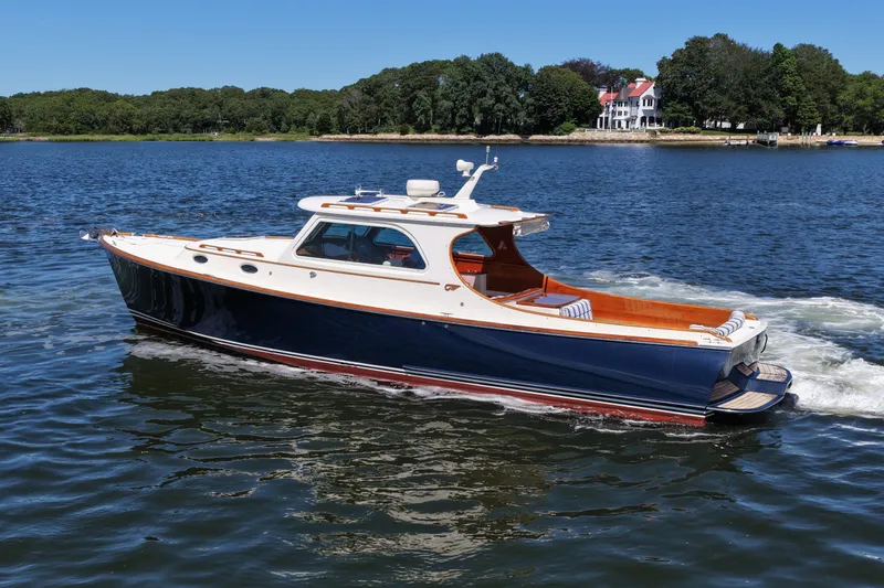  Yacht Photos Pics 2005 Hinckley 36 yacht cruising on a serene lake with lush green shoreline.