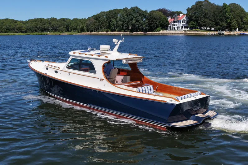  Yacht Photos Pics 2005 Hinckley 36 yacht cruising on a serene lake with lush greenery in the background.