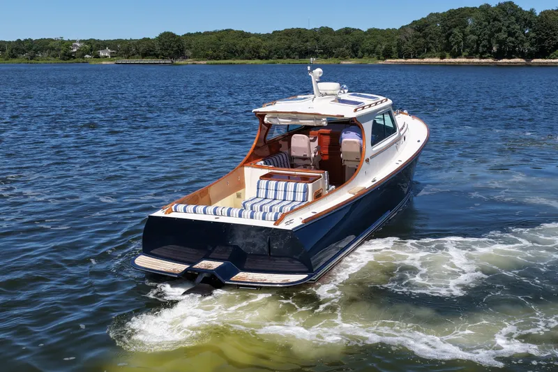  Yacht Photos Pics 2005 Hinckley 36 boat cruising on a serene lake with lush green shoreline.