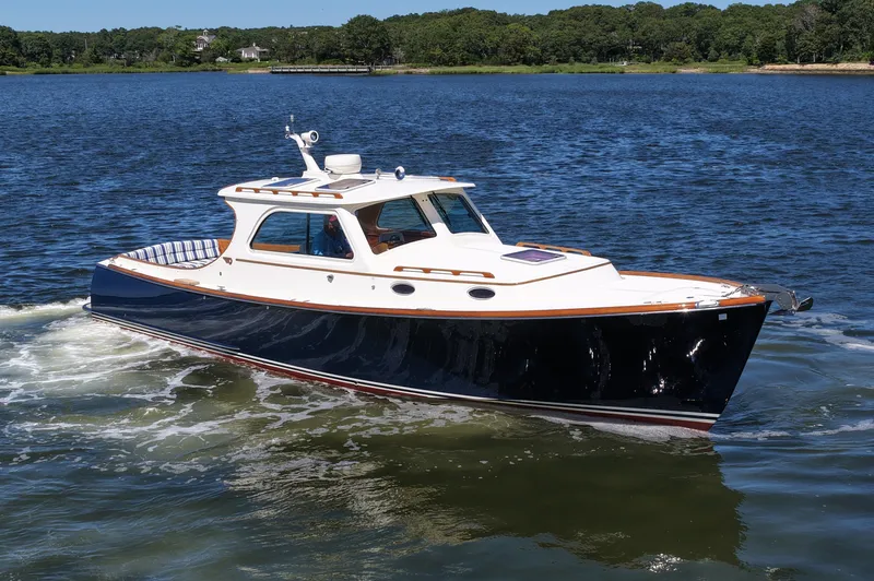  Yacht Photos Pics 2005 Hinckley 36 boat cruising on a calm lake with lush green shoreline.