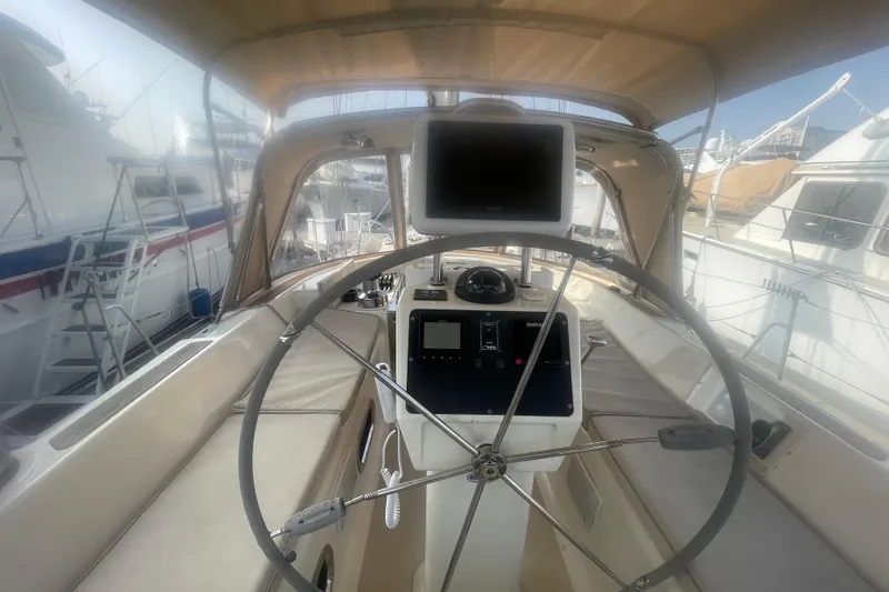 Peetee Hana Yacht Photos Pics 2008 Caliber center cockpit cutter with steering wheel and navigation equipment in marina.