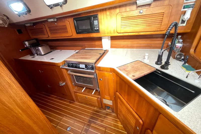Peetee Hana Yacht Photos Pics 2008 Caliber center cockpit cutter kitchen with wooden cabinetry and modern appliances.
