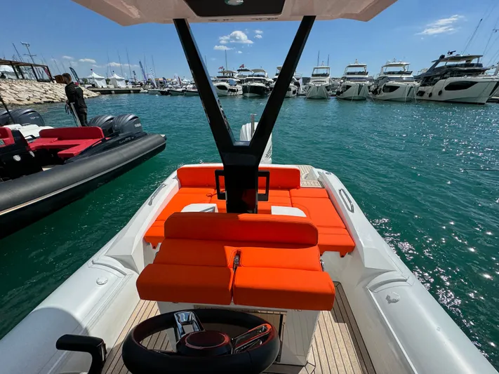  Yacht Photos Pics 2025 SuperRib Open 27 boat with orange seating, docked at a marina with yachts.