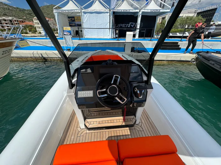  Yacht Photos Pics 2025 SuperRib Open 27 boat dashboard with steering wheel and orange seating at marina.