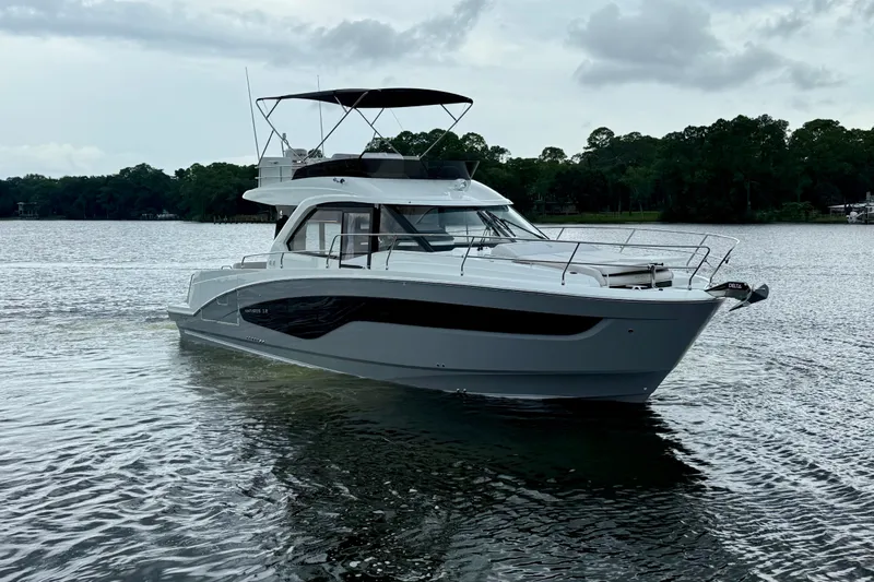  Yacht Photos Pics 2026 Beneteau Antares 12 yacht on a serene lake with lush green background.