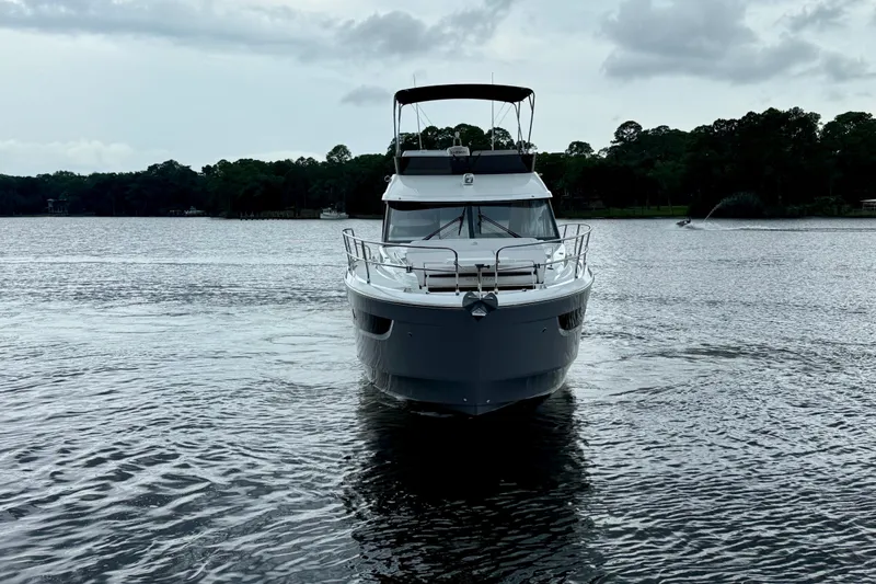  Yacht Photos Pics 2026 Beneteau Antares 12 yacht on a serene lake with lush tree backdrop.