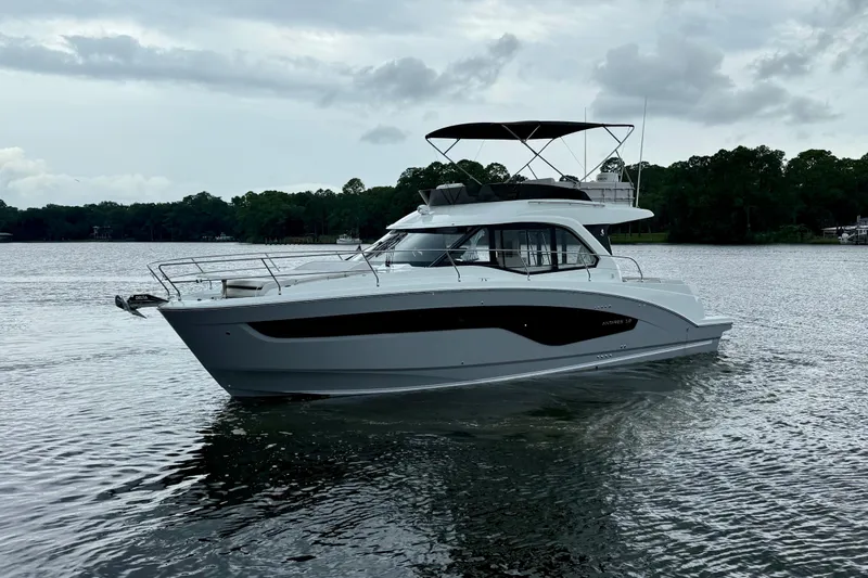  Yacht Photos Pics 2026 Beneteau Antares 12 yacht on a serene lake under cloudy skies.