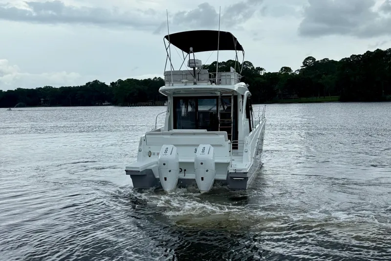  Yacht Photos Pics 2026 Beneteau Antares 12 cruising on a calm lake under cloudy skies.