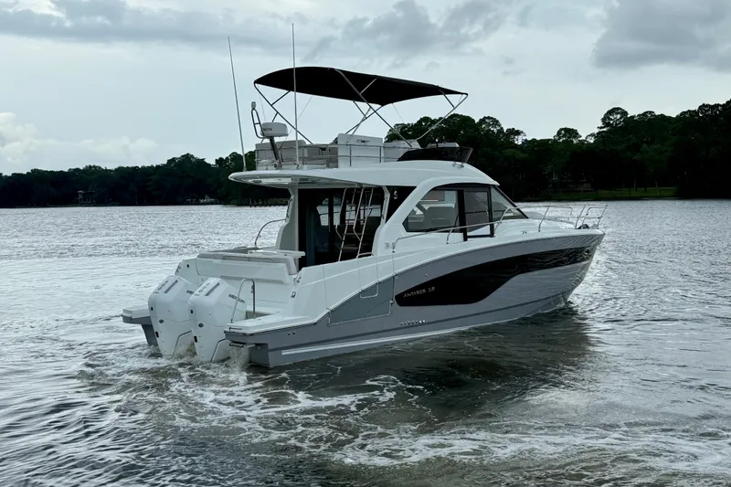 Yacht Photos Pics 2026 Beneteau Antares 12 yacht cruising on a serene lake under cloudy skies.