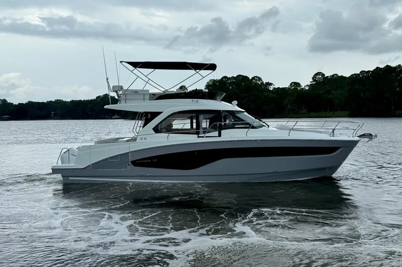  Yacht Photos Pics 2026 Beneteau Antares 12 yacht cruising on a calm lake under cloudy skies.