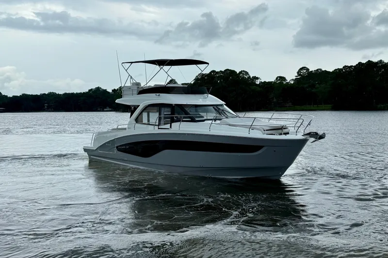  Yacht Photos Pics 2026 Beneteau Antares 12 yacht cruising on a serene lake under cloudy skies.