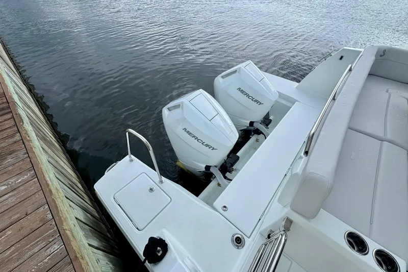  Yacht Photos Pics 2026 Beneteau Antares 12 with dual Mercury outboard engines docked by wooden pier.