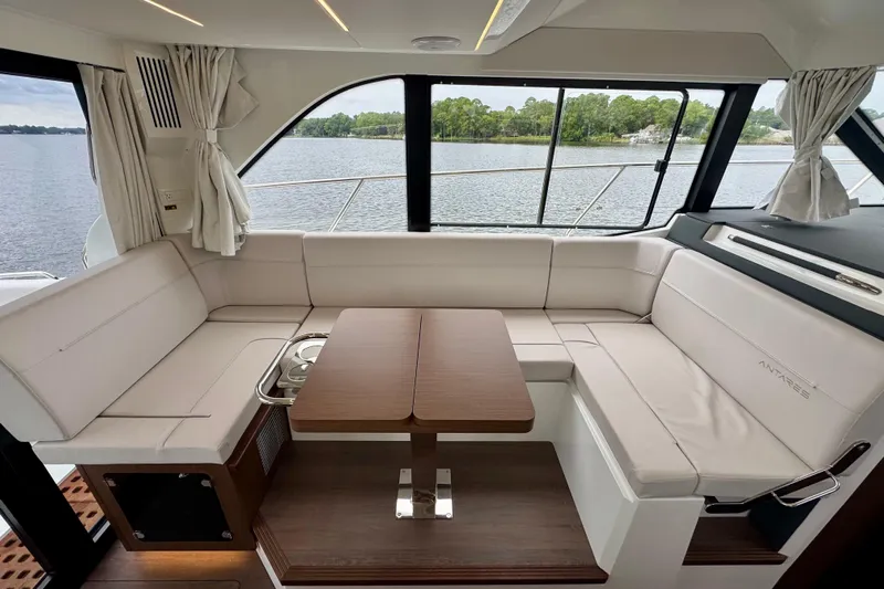  Yacht Photos Pics Luxurious interior of 2026 Beneteau Antares 12 yacht with elegant seating and wooden table.