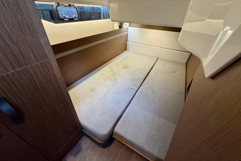  Yacht Photos Pics 2026 Beneteau Antares 12 cabin interior with wooden finish and cozy bedding.