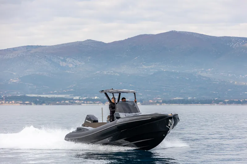  Yacht Photos Pics 2026 SuperRib Open 27 boat cruising on calm water with mountainous backdrop.