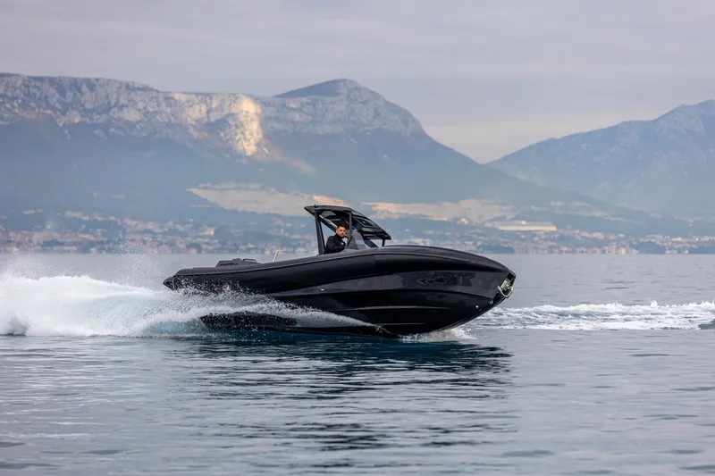  Yacht Photos Pics A sleek 2026 SuperRib Open 27 boat cruising on calm waters with mountainous backdrop.