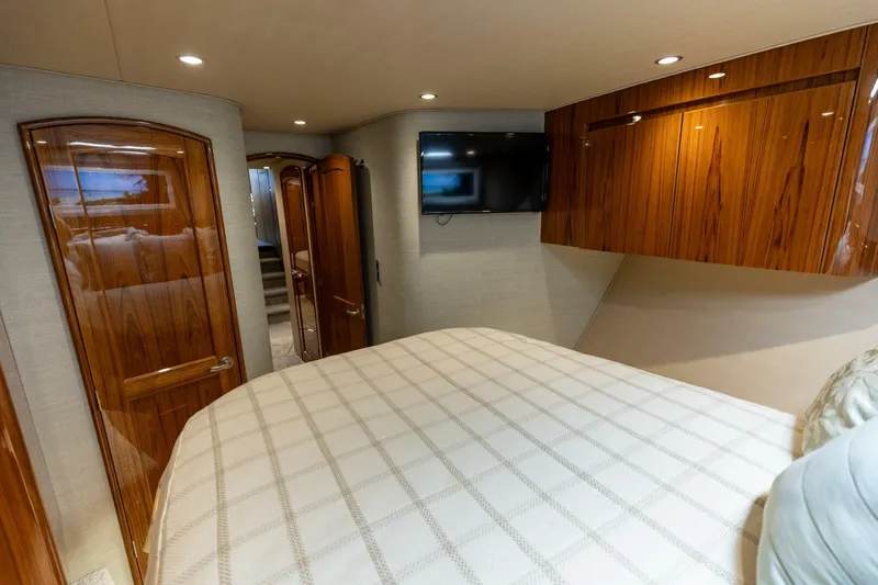 Gas Money Yacht Photos Pics Luxurious bedroom interior of 2015 Viking 62 Convertible yacht with wood finishes and TV.
