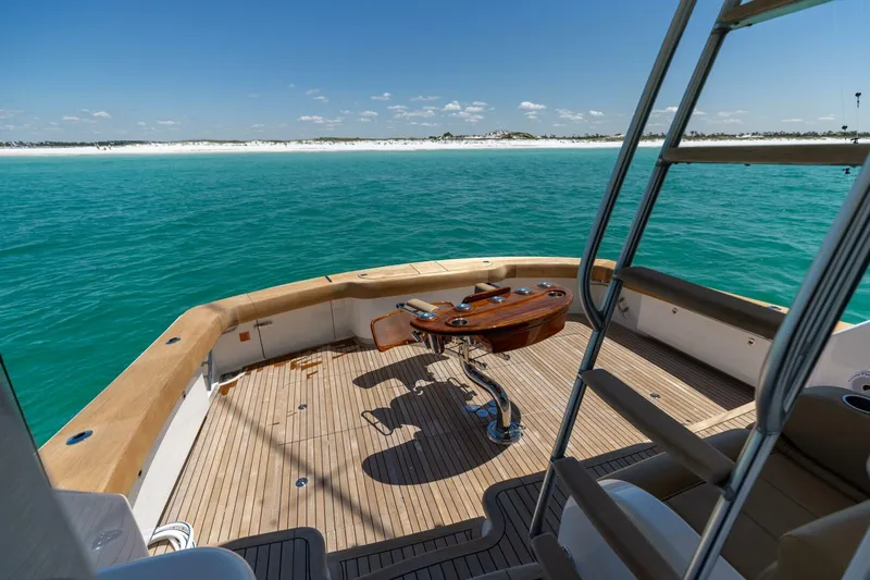 Gas Money Yacht Photos Pics 2015 Viking 62 Convertible yacht deck overlooking turquoise ocean and sandy shoreline.