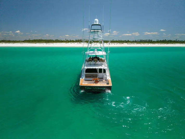 Gas Money Yacht Photos Pics 2015 Viking 62 Convertible yacht cruising in turquoise waters near a sandy beach.