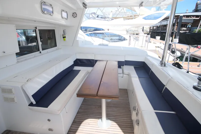 Sv Hypnautic Yacht Photos Pics Spacious seating area on a 2002 Lagoon 440 catamaran with wooden table and cushioned benches.