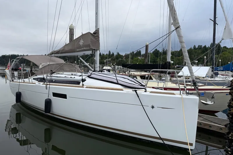 A Bientot Yacht Photos Pics 2016 Jeanneau Sun Odyssey 349 sailboat docked in a marina, overcast sky.