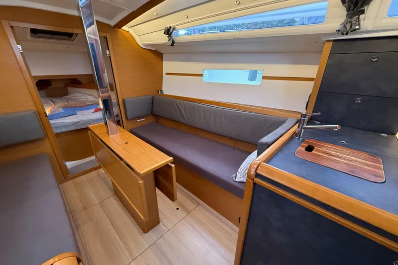 A Bientot Yacht Photos Pics Interior of 2016 Jeanneau Sun Odyssey 349 sailboat, featuring cozy seating and compact kitchen area.